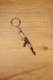 AK-74 style rifle keychain with metal ring and chain on wooden table, tactical gaming accessory for FPS and shooter fans