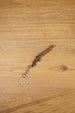 Mini double-barrel shotgun keychain displayed diagonally on wood, featuring gunmetal barrels, brown stock detail and silver keyring