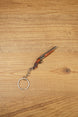 Mini double-barrel shotgun keychain displayed diagonally on wood, featuring gunmetal barrels, brown stock detail and silver keyring
