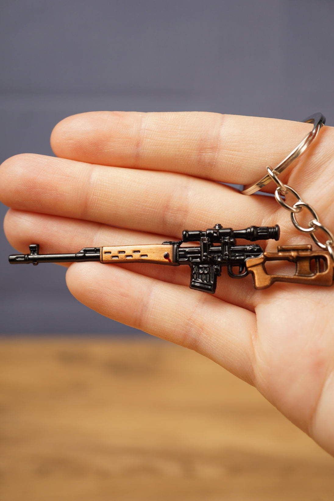 Miniature SVDS rifle metal keychain resting in a hand, showing scale, tactical details and sturdy split ring attachment