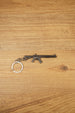 MK47 metal rifle keyring laid flat on a wooden surface, showing the full miniature tactical design with chain and split ring