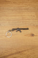 MK47 metal rifle keyring laid flat on a wooden surface, showing the full miniature tactical design with chain and split ring