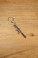 Detailed metal rifle keyring with tactical MK47-style shape, chain and key loop displayed on a wooden background for collectors
