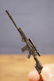 Close-up of modded SA58 FAL rifle keychain held upright, showing scope, rail detail, magazine and tactical stock design