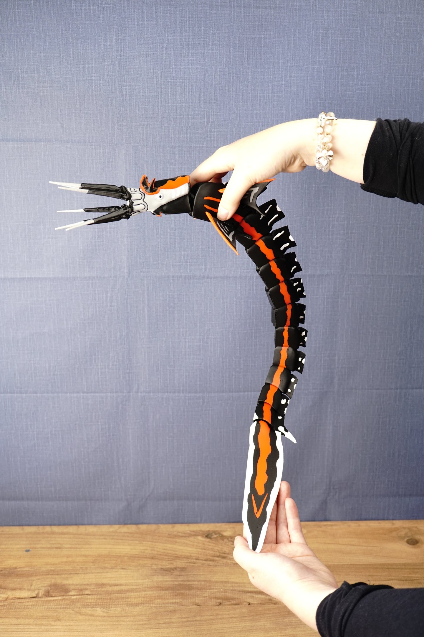 Full-length Needler Mango collectible held in a curved swimming pose, demonstrating the movement of its segmented body and oversized decorative tail.