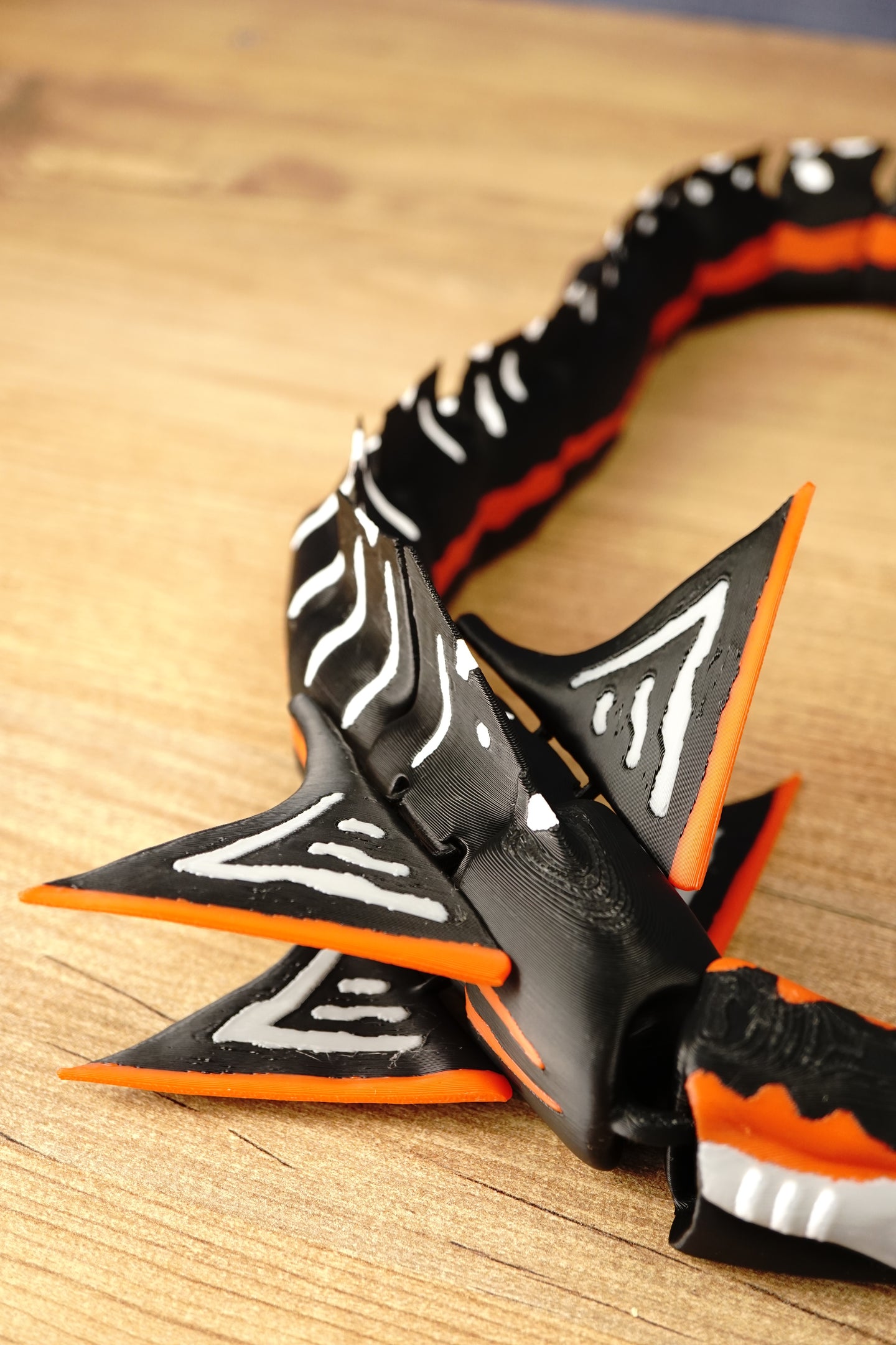 Close-up of the Needler Mango model’s layered fins, featuring black surfaces, white patterns and bright orange edges beside the segmented body.