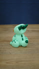 Rear and side view of the Nibbles the Drake Palia collectible showing dark green horns, back markings, spotted legs and green tipped baby drake tail