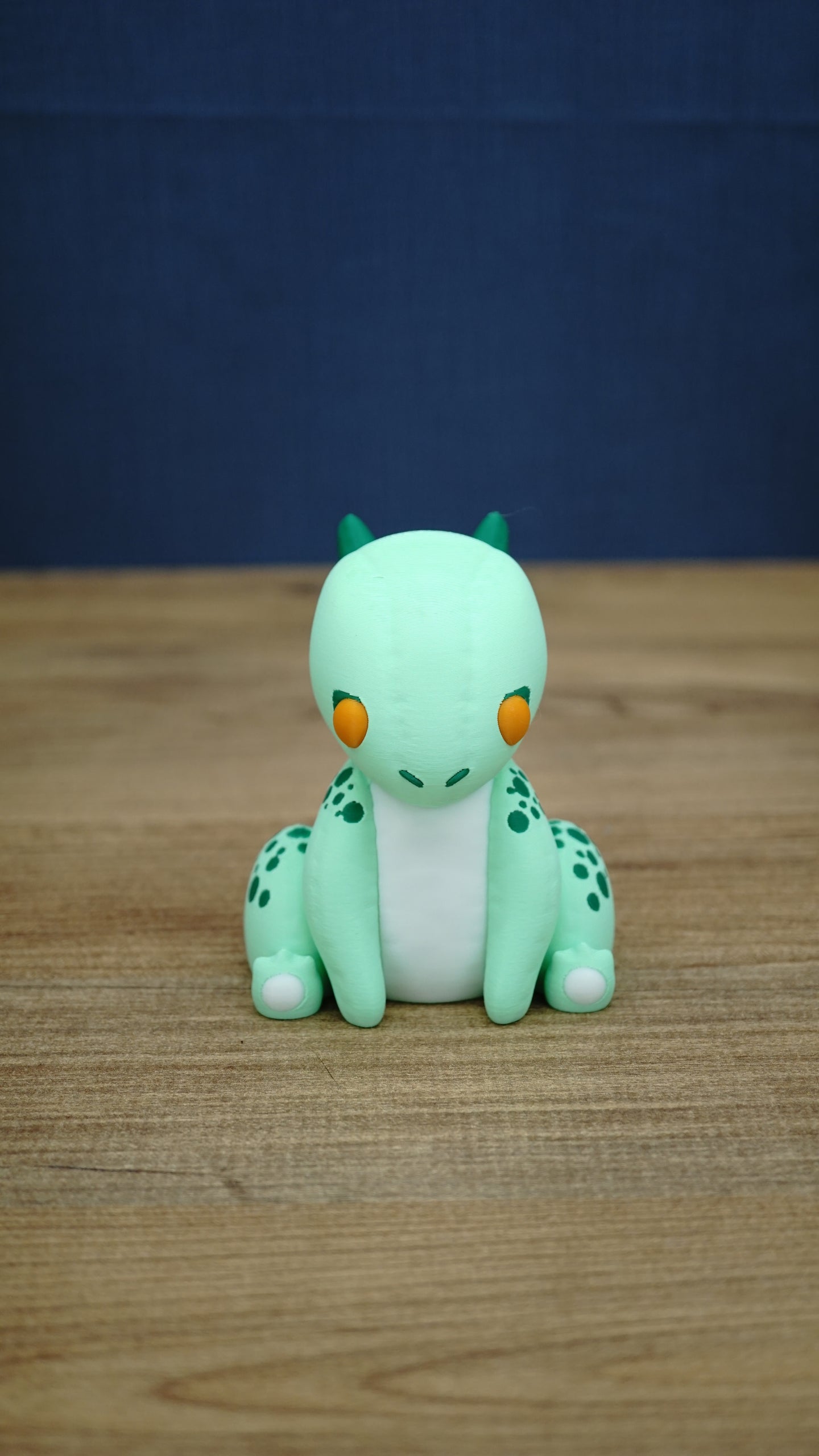 Front view of Nibbles the Drake Palia collectible figure with mint green body, orange eyes, white belly, dark green horns and spotted markings