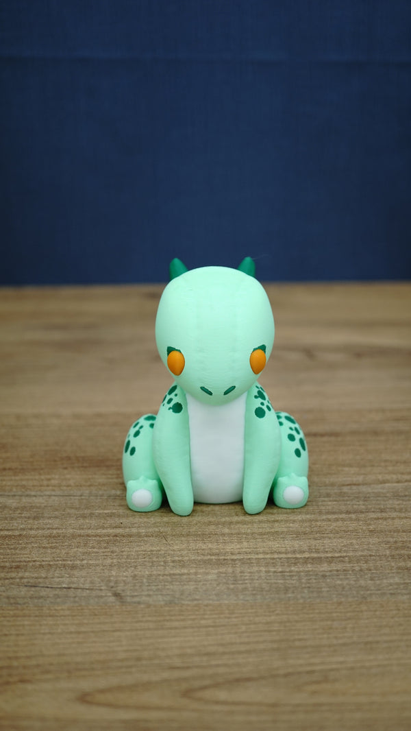 Front view of Nibbles the Drake Palia collectible figure with mint green body, orange eyes, white belly, dark green horns and spotted markings