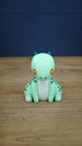 Front view of Nibbles the Drake Palia collectible figure with mint green body, orange eyes, white belly, dark green horns and spotted markings