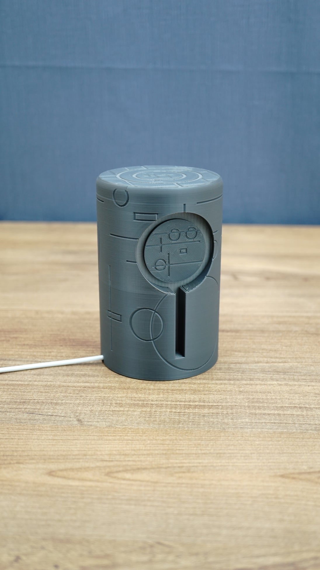 No Man’s Sky inspired Knowledge Stone LED light shown unlit on a wooden desk, featuring a dark grey sci-fi cylindrical body and engraved alien details.