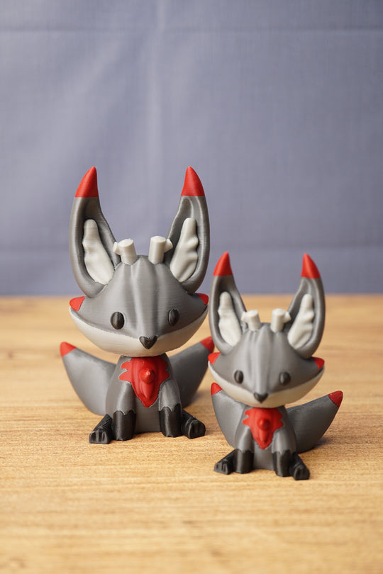 Obsidian Kitsuu figures in large and small sizes with grey bodies, red accents, black paws and cute fox-like faces