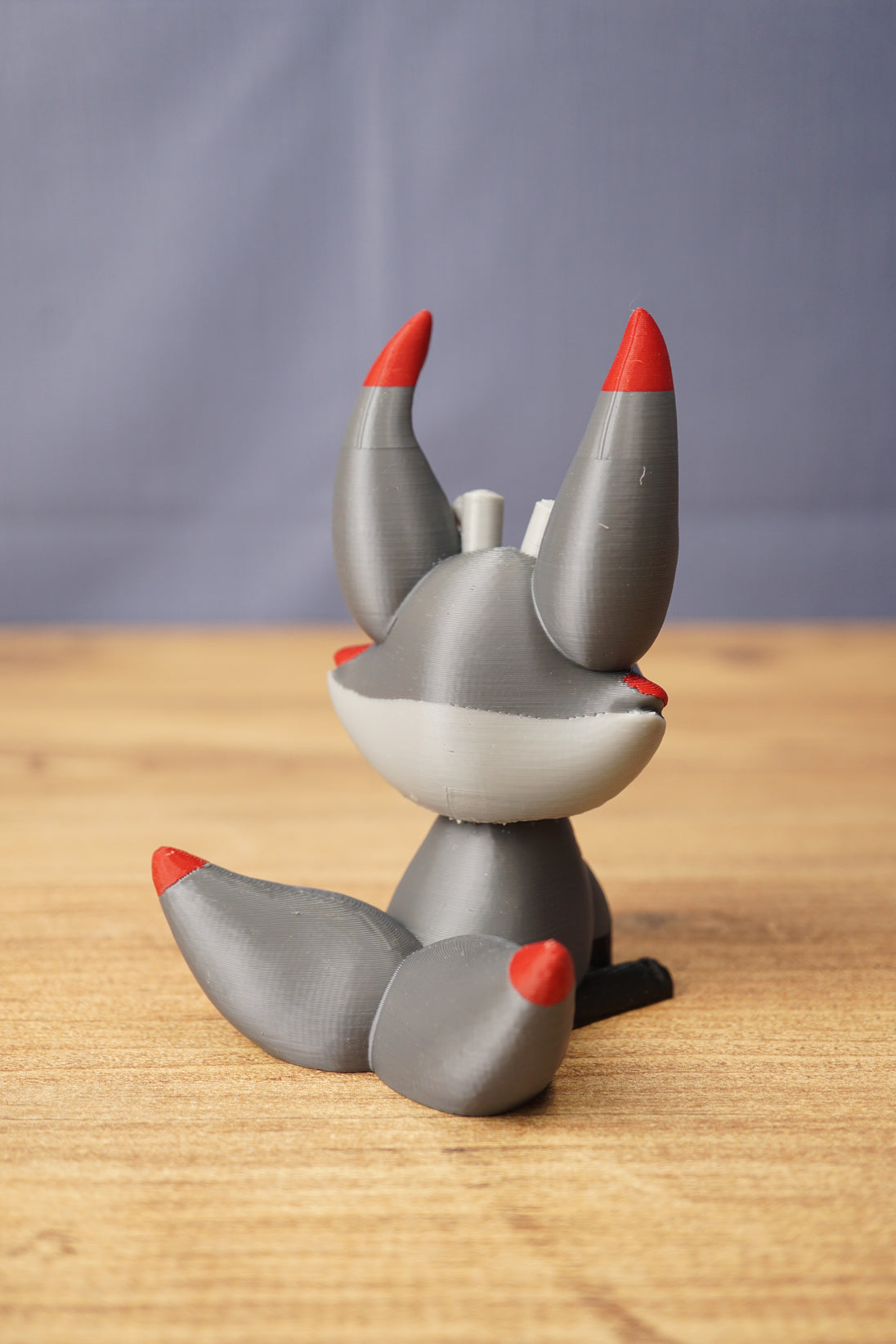 Rear view of Obsidian Kitsuu figure showing grey curled tail, red tail tip, tall ears and white back head detail