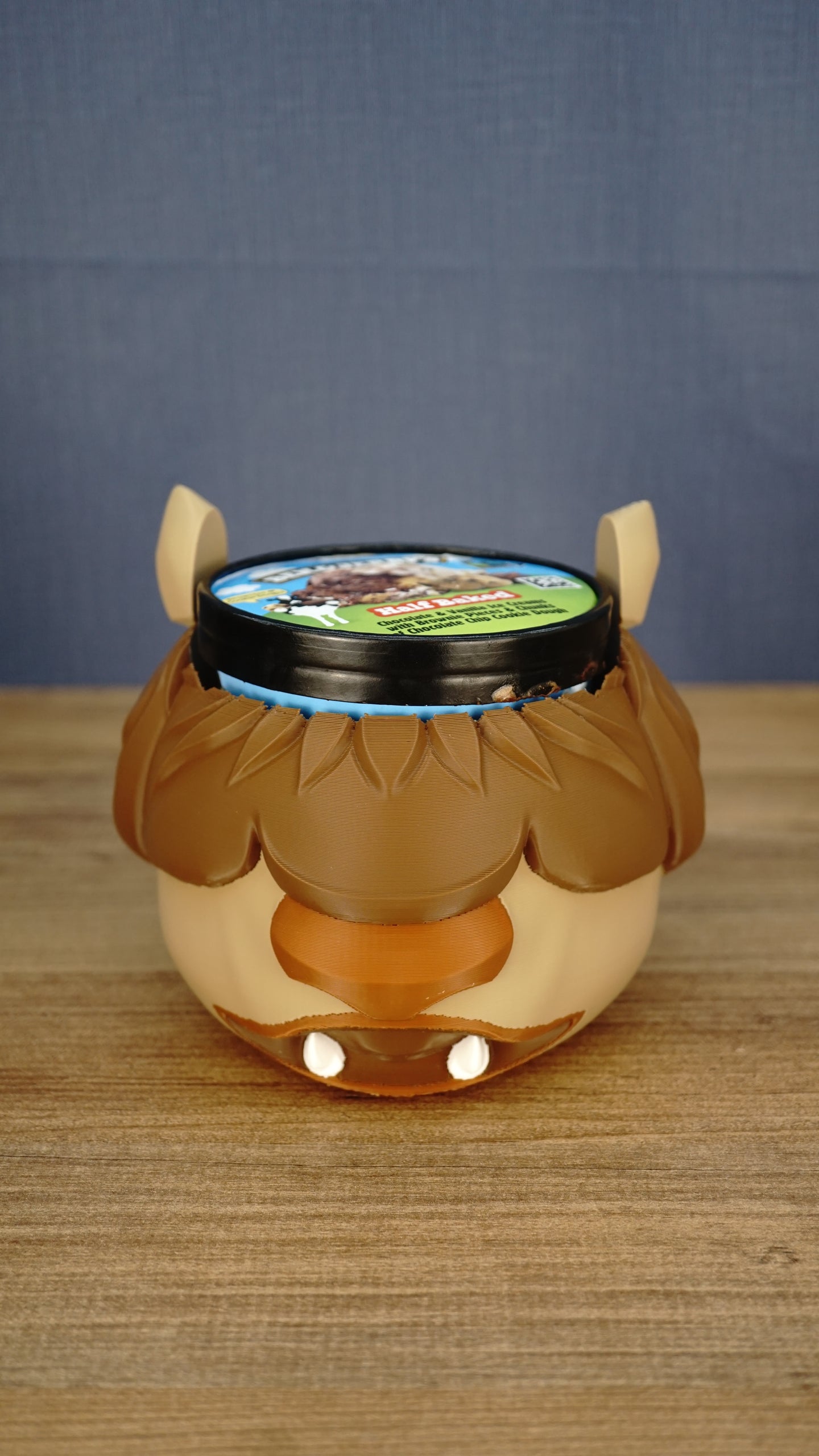 Front view of a lidded packaged ice cream tub fitted inside the Ormuu Shack character holder, demonstrating the holder’s opening and overall fit.