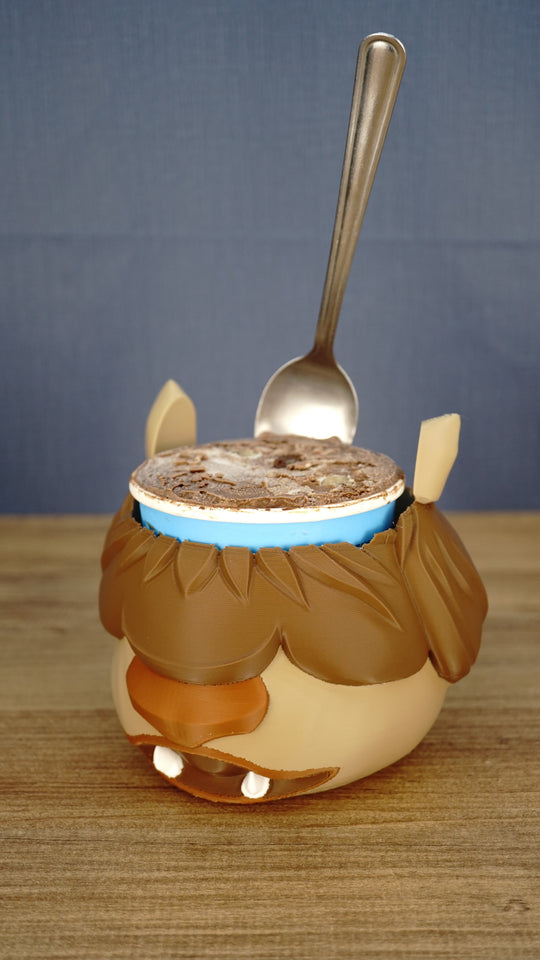 Front view of the Ormuu Shack holder containing a packaged ice cream tub with a spoon, demonstrating how the tub fits inside the character design.