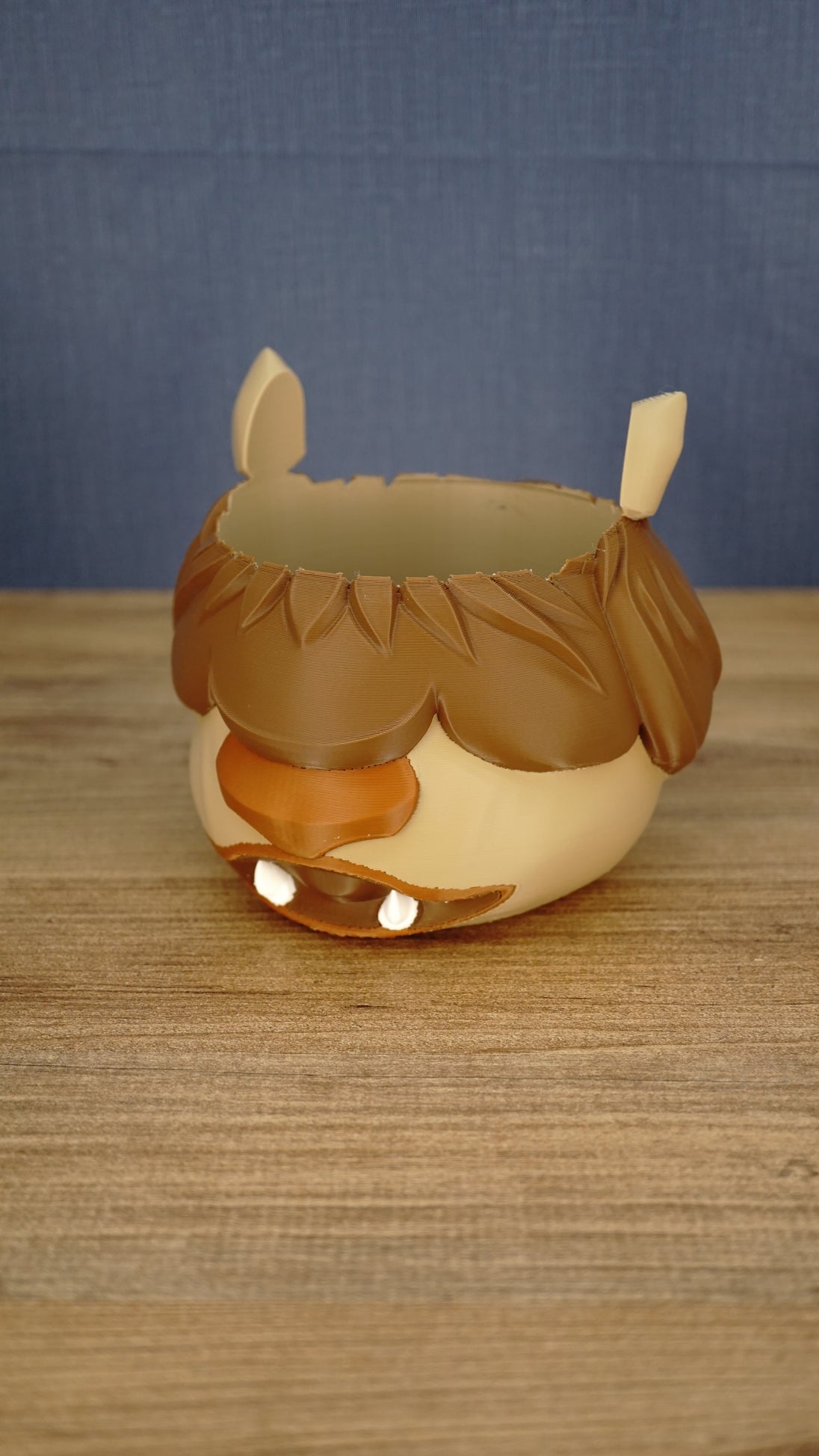 Front angled view of a Palia-inspired Ormuu Shack ice cream tub holder with brown fringe, cream face, pointed ears, orange muzzle and white teeth.