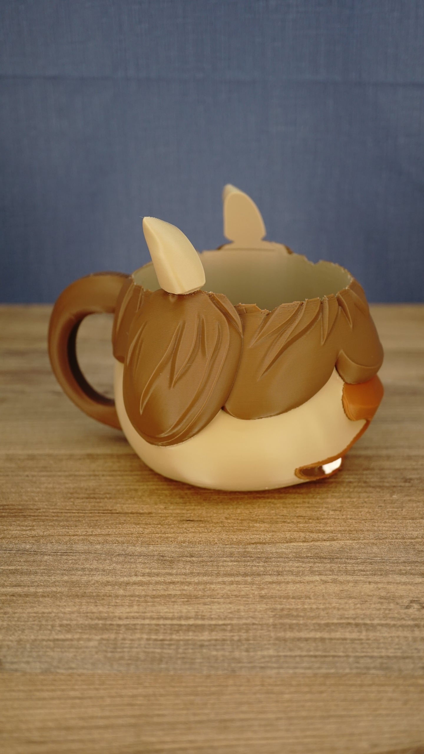 Side view of the Ormuu Shack character ice cream tub holder showing its large brown handle, layered fringe, cream body and small muzzle.