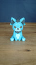 Front view of a blue 3D printed Palcat plush figure with amber eyes, dark grey accents, white muzzle, tiny fangs, and white paw pads.