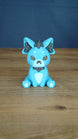 Front view of a blue 3D printed Palcat plush figure with amber eyes, dark grey accents, white muzzle, tiny fangs, and white paw pads.
