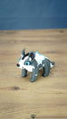Bluebristle Muujin plush-inspired figure from Palia shown at an angle, featuring bright blue eyes, a grey body, a white mane and turquoise blue spikes.