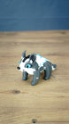 Bluebristle Muujin plush-inspired figure from Palia shown at an angle, featuring bright blue eyes, a grey body, a white mane and turquoise blue spikes.