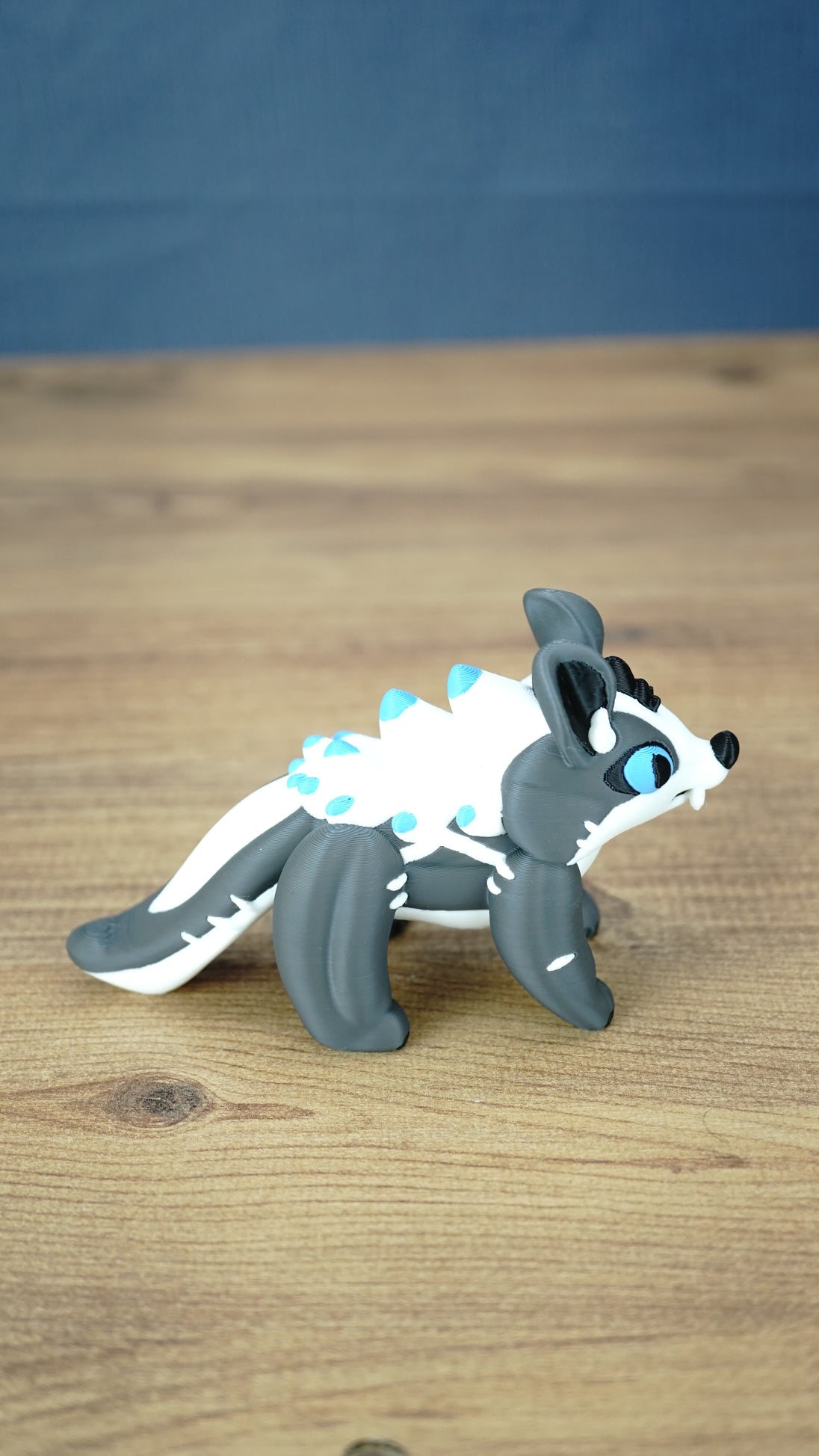 Side view of a Palia Bluebristle Muujin figurine with vivid blue eyes, grey legs, oversized ears, white spiky mane and decorative turquoise blue details.
