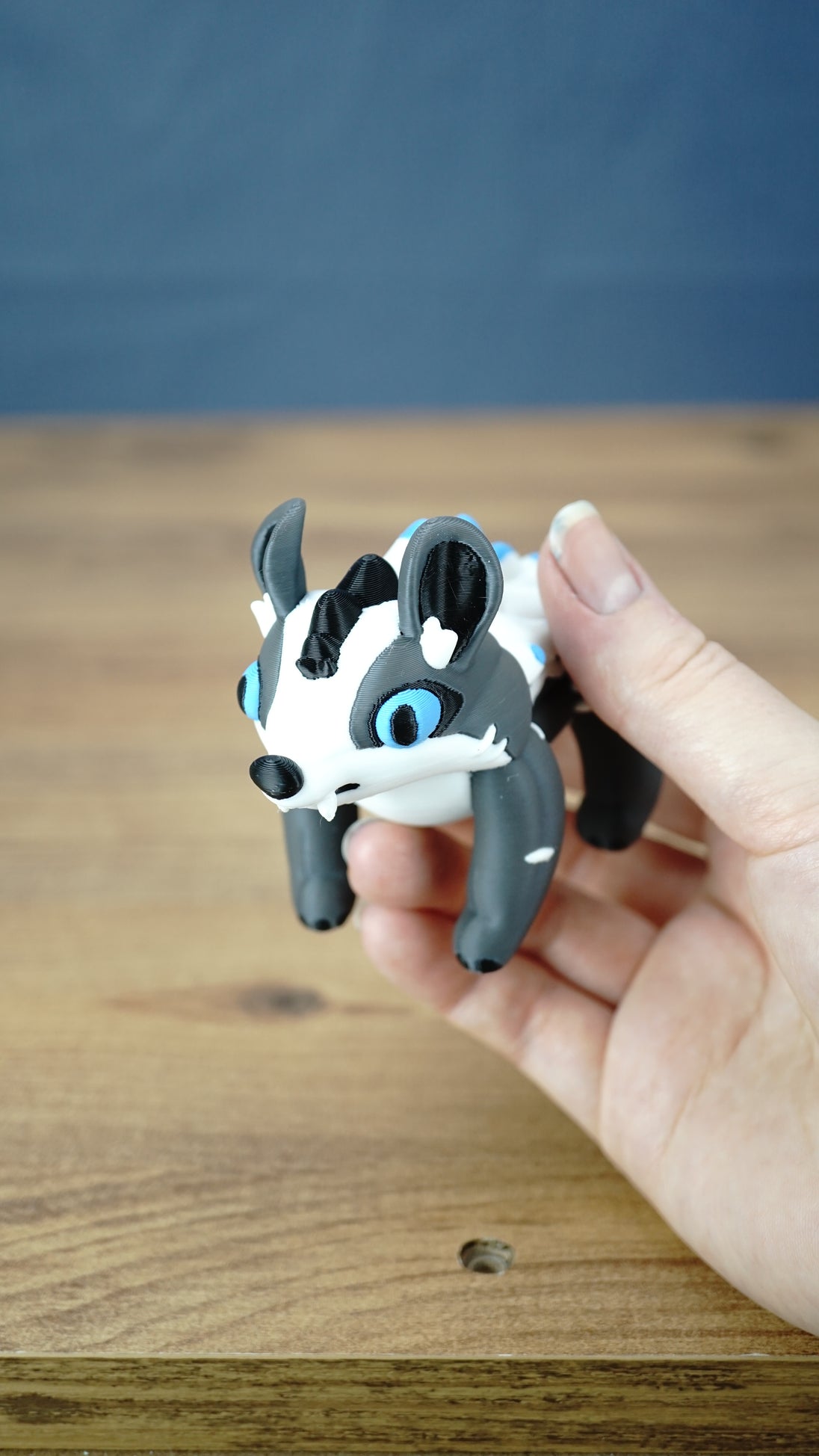 Handheld Palia Bluebristle Muujin collectible figure showing its adorable blue-eyed face, upright ears, white facial markings and compact tabletop display size.