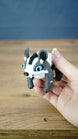 Handheld Palia Bluebristle Muujin collectible figure showing its adorable blue-eyed face, upright ears, white facial markings and compact tabletop display size.