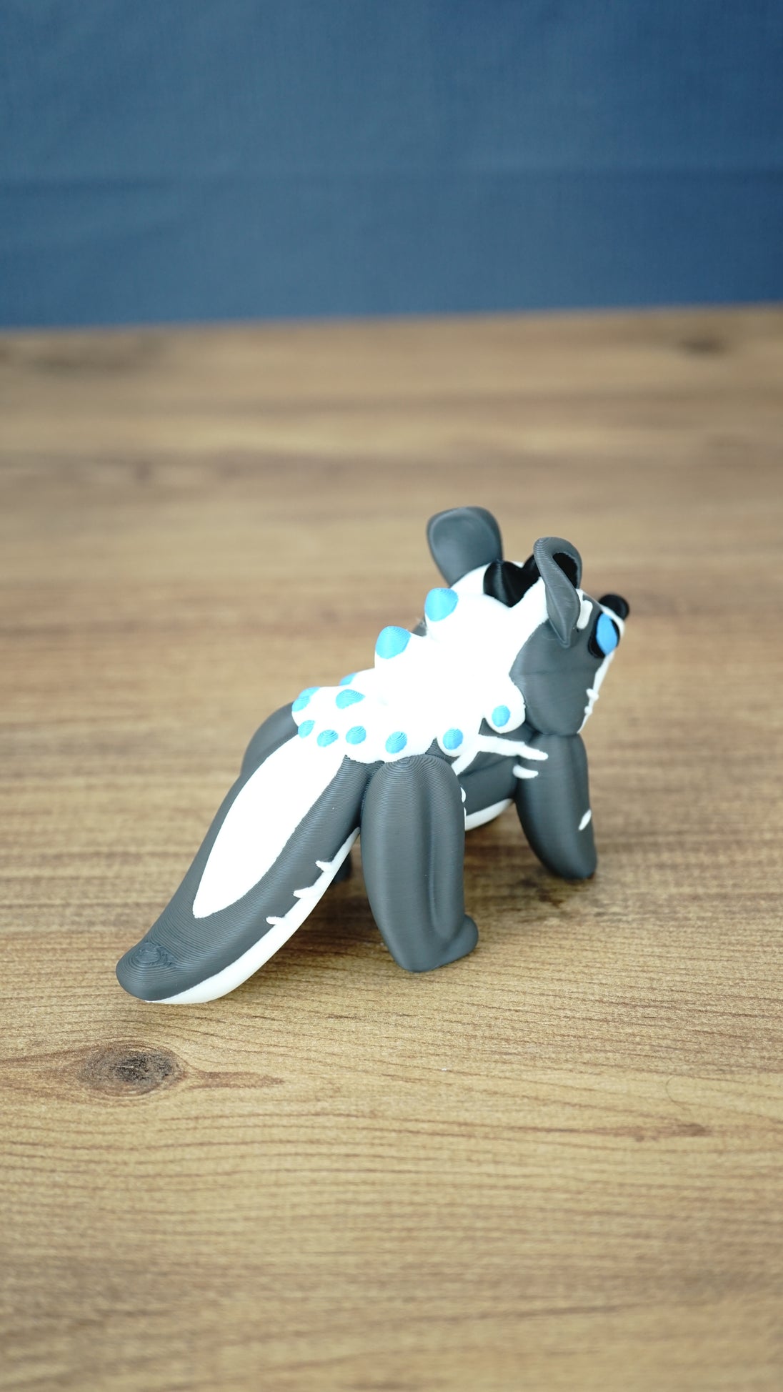 Rear view of the Palia Bluebristle Muujin collectible figure displaying its long grey and white tail, white fantasy creature mane and turquoise blue accents.