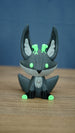 Front view of a Cave Kitsuu 3D printed figure with glowing green eyes, dark green ears, black paws, and bright green feet.