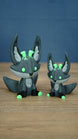 Large and small Cave Kitsuu 3D printed figures side by side, featuring dark green bodies, bright green accents, tall ears, and curled tails.