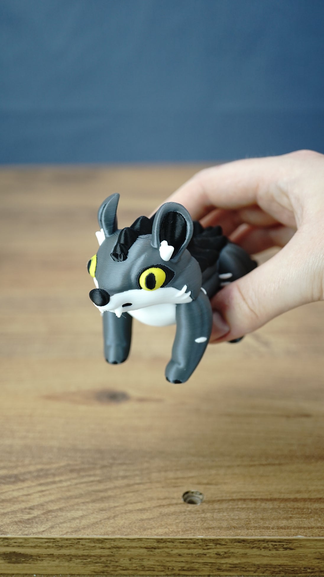 Hand holding a classic Palia Muujin collectible figure with yellow eyes, large pointed ears and a cute grey wolf-like face, demonstrating its compact display size