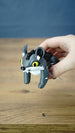 Hand holding a classic Palia Muujin collectible figure with yellow eyes, large pointed ears and a cute grey wolf-like face, demonstrating its compact display size
