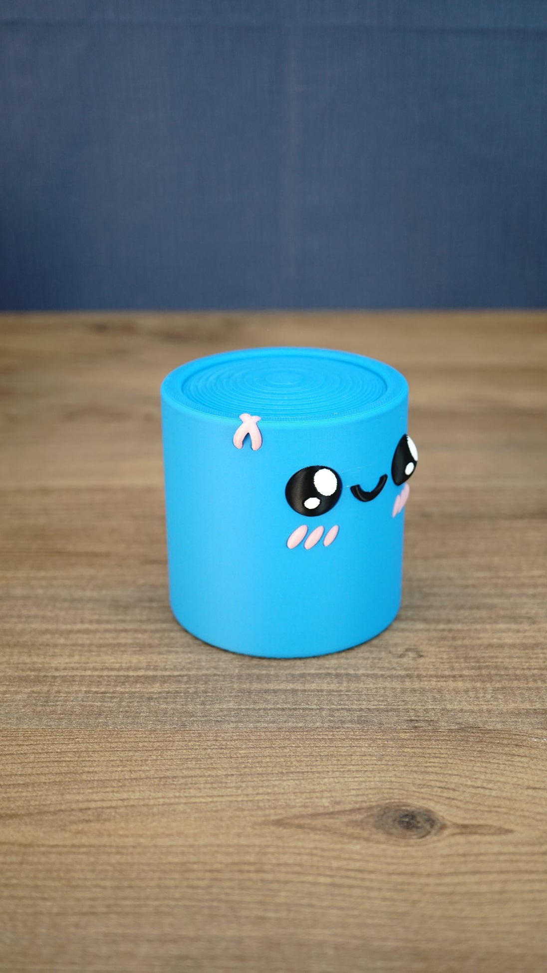 Angled side view of the blue Palia Cyl Cylinder Collectible showing its rounded cylindrical shape and cute face.