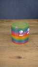 Angled view of a rainbow Palia Cyl Cylinder collectible showing the colorful striped body, spiral top texture, and cute face details.