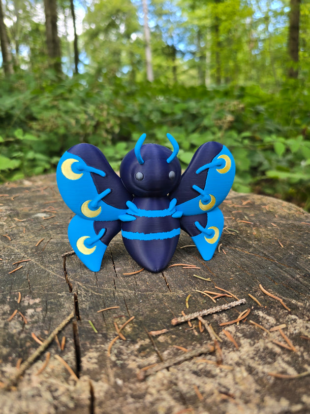 3D printed Palia-inspired Duskwing Butterfly plush figure with dark navy body, bright blue wing details, and yellow crescent markings, displayed on a forest tree stump.