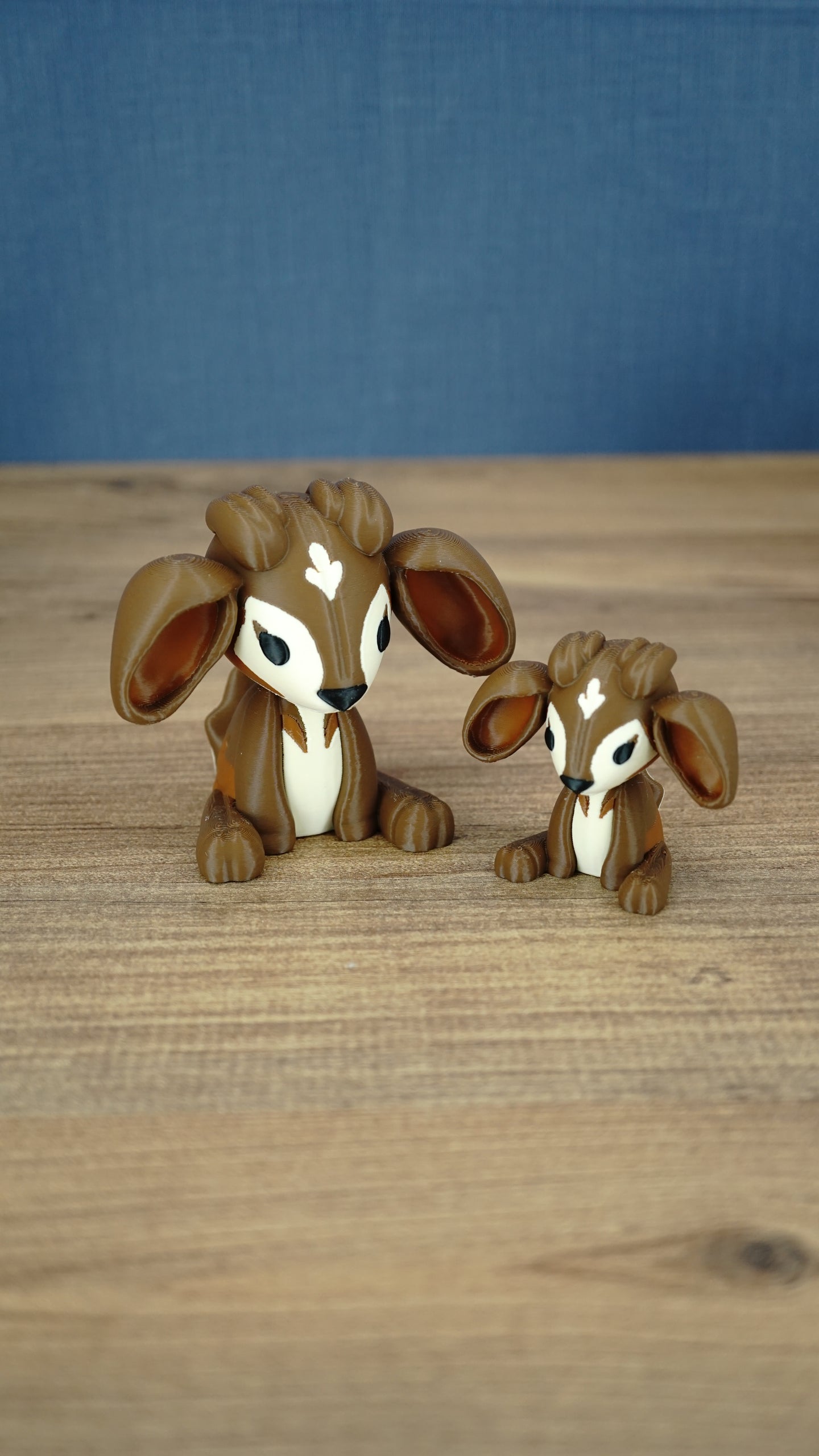 Large and small Elder Sernuk-inspired Palia plush figures displayed together on a wooden tabletop.