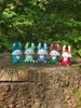 Five colourful 3D printed Palia Flutterfox plush figures displayed in a row on a tree stump in a forest.