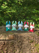 Five colourful 3D printed Palia Flutterfox plush figures displayed in a row on a tree stump in a forest.