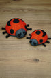 Palia Garden Ladybug Plush collectibles in 11cm and 8cm sizes, showing red and black ladybug designs together on a wooden display surface.