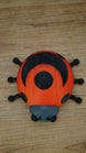 Top view of the Palia Garden Ladybug Plush collectible showing its distinctive red shell, large black wing markings, central spot and six black legs.