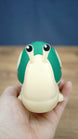Palia Garden Snail Plush collectible held in a hand to demonstrate its compact size, with a cream body, green shell and expressive raised eyes