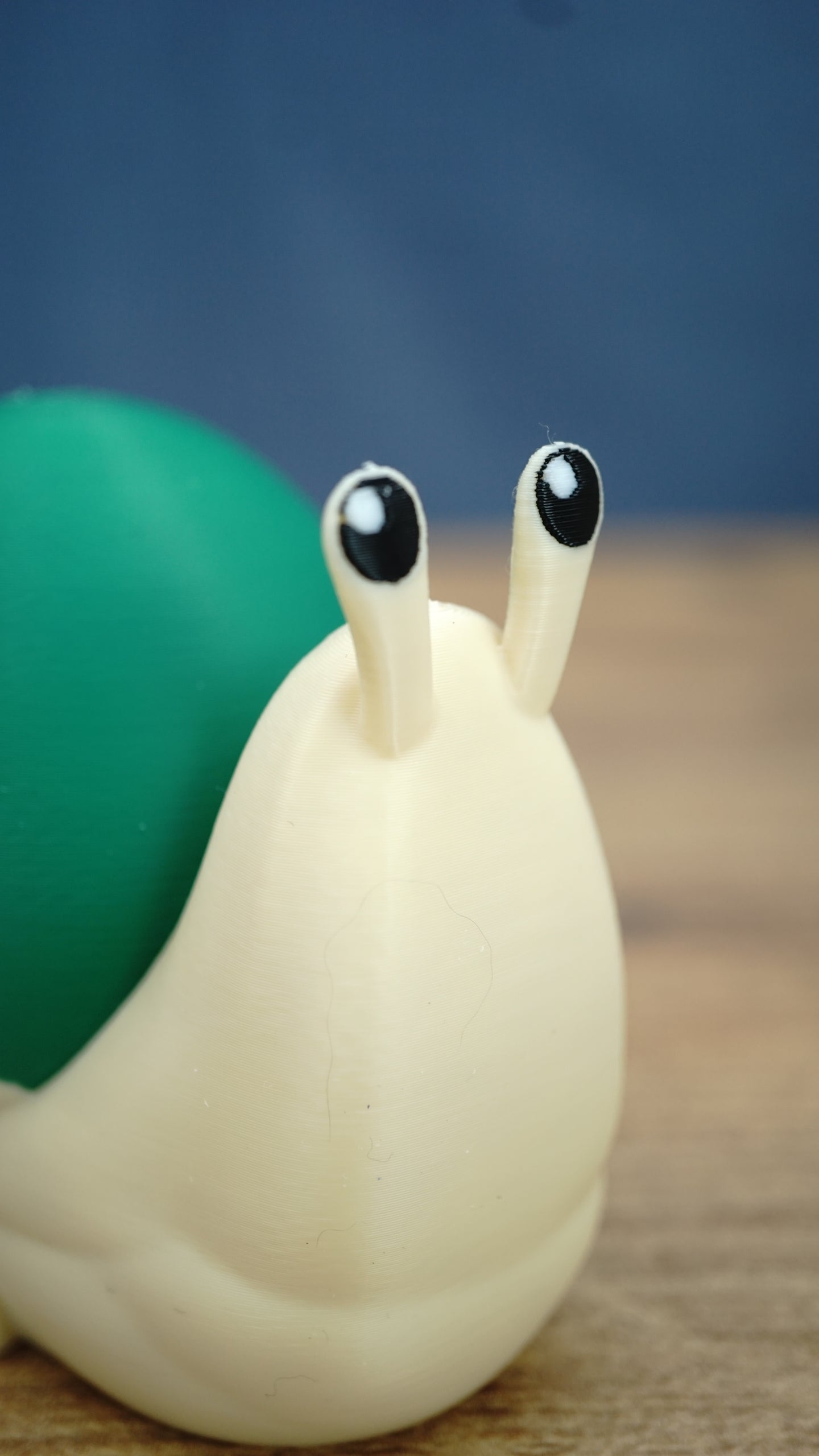 Close-up of the Palia Garden Snail Plush figure showing its adorable raised eye stalks, black and white eyes, cream body and green shell