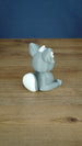 Back side view of a grey 3D printed Palcat plush figure showing its curled white-tipped tail, large ears, and seated pose.