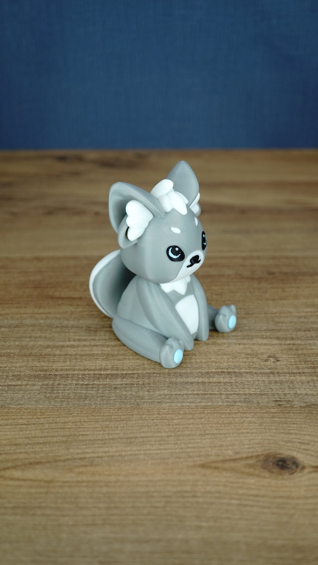 Side view of a grey 3D printed Palcat plush figure showing large ears, white ear tufts, black eyes, and a curled white-tipped tail.