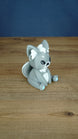 Side view of a grey 3D printed Palcat plush figure showing large ears, white ear tufts, black eyes, and a curled white-tipped tail.