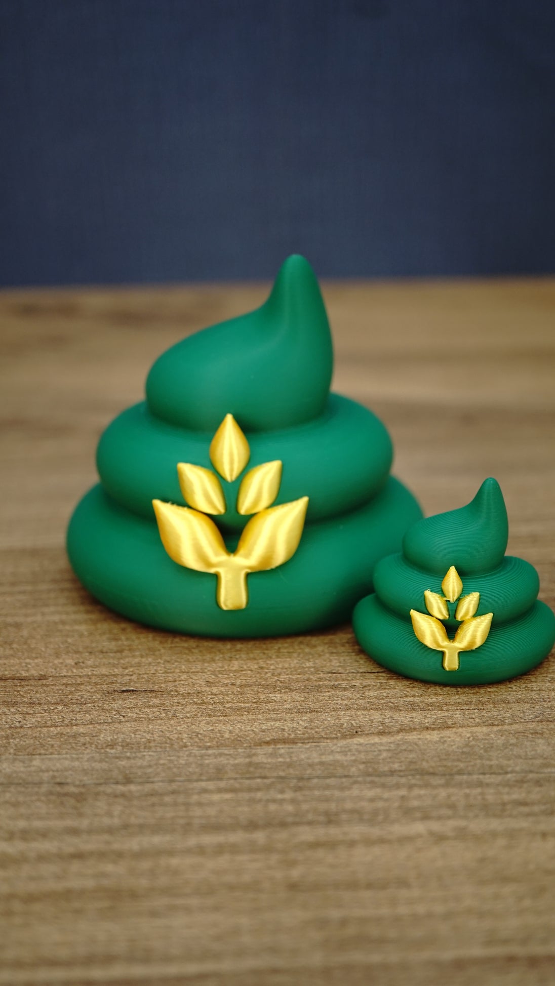 Large and small HarvestBoost Palia fertilizer collectibles in a classic brown finish, displayed together on a wooden tabletop.