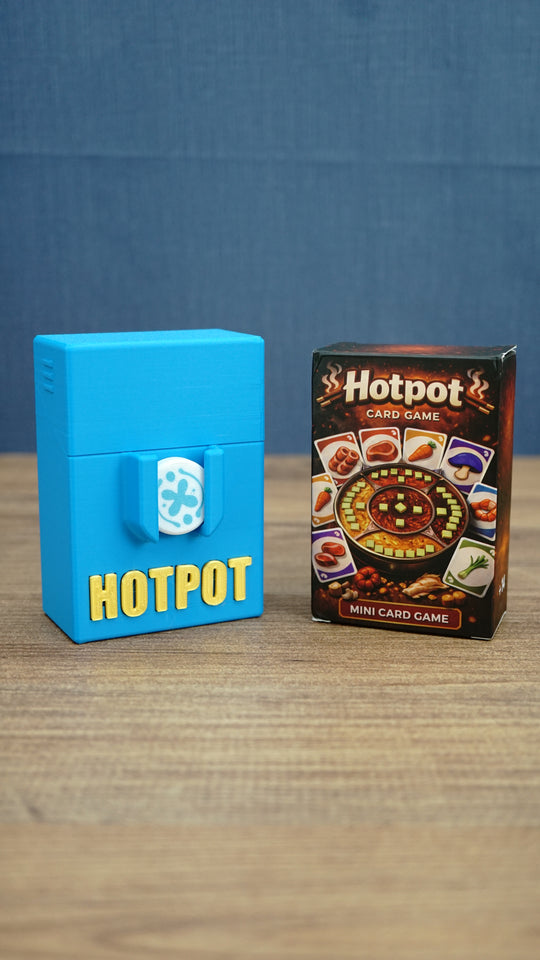 Palia Hotpot mini card game box displayed beside a blue 3D printed Hotpot storage case with gold lettering and a white pass token on the front.
