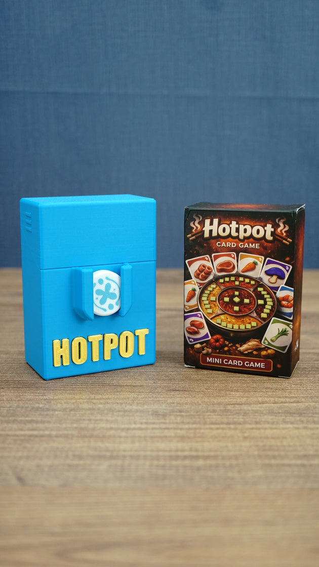 Palia Hotpot mini card game box displayed beside a blue 3D printed Hotpot storage case with gold lettering and a white pass token on the front.