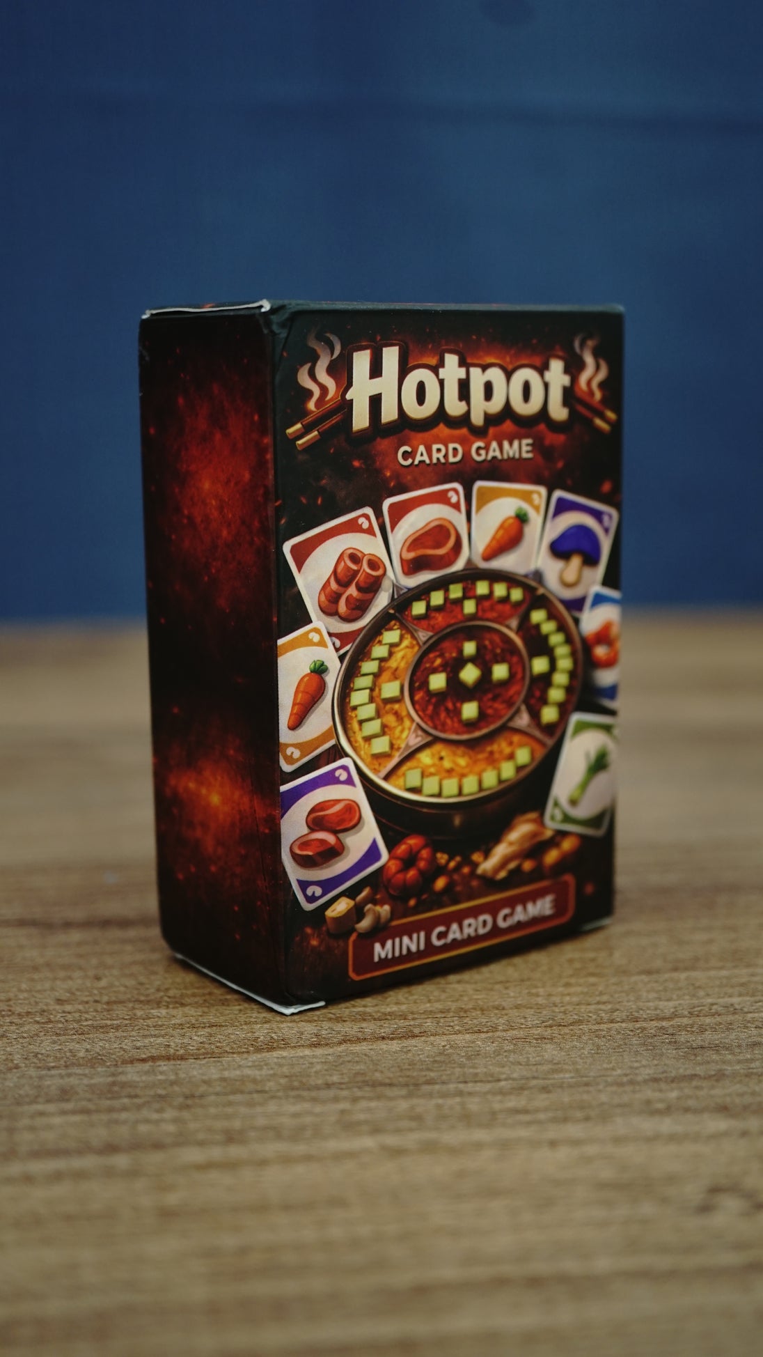 Angled view of the Palia-inspired Hotpot card game box showing the illustrated front design, ingredient cards, and dark red side panel.